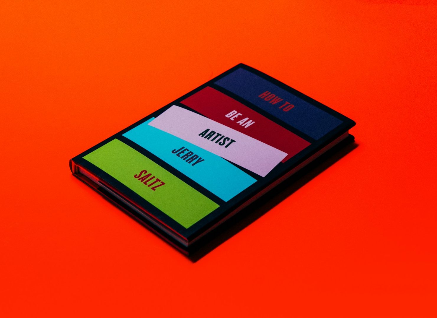 A stacked set of colorful notebooks on a bright orange background.